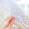 A hand touches a sheet of iridescent 3D decorative window privacy film.