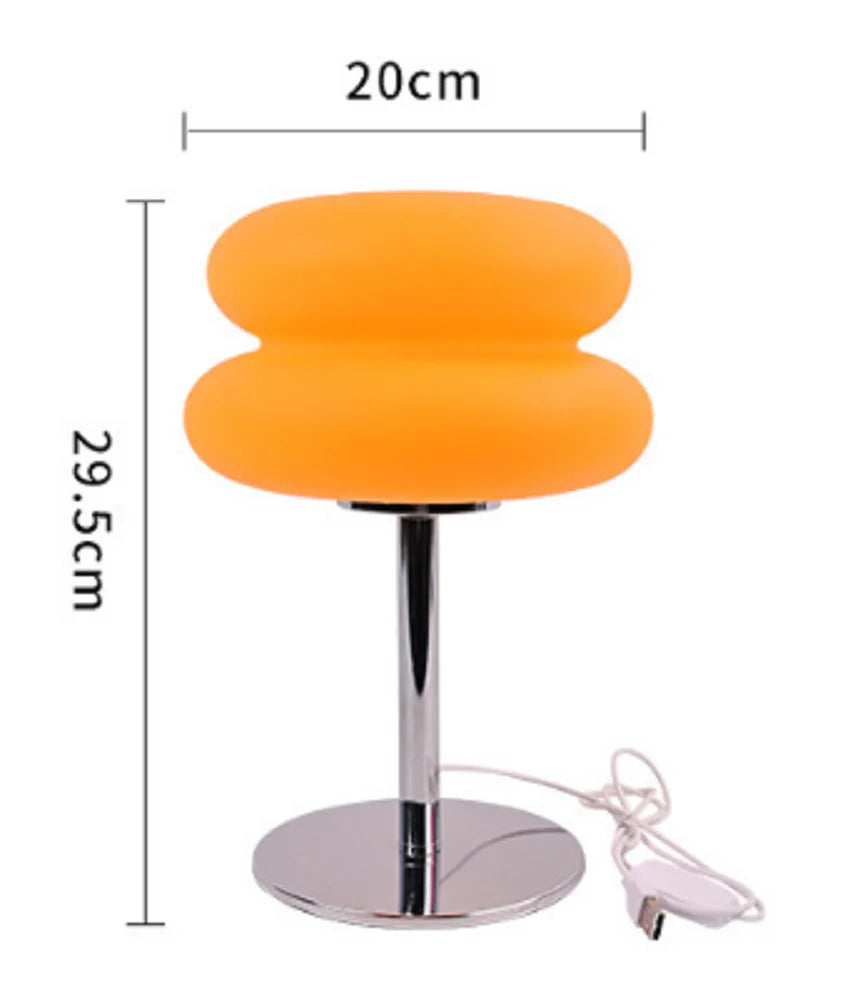 Lámpara de mesilla de noche ajustable estilo crema naranja con base y cable plateado.