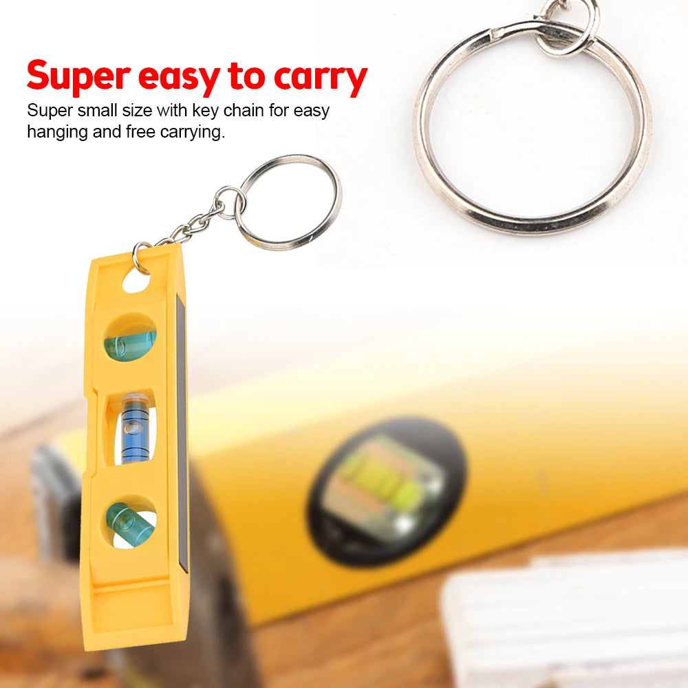 Yellow mini bubble level with a keychain attached, shown next to a yellow object.