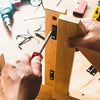 A hand is using a screwdriver bit holder to secure a wooden piece, showing the tool in action.