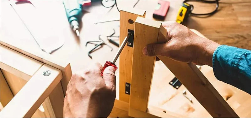 A hand is using a screwdriver bit holder to secure a wooden piece, showing the tool in action.