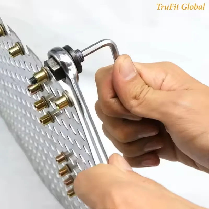 A hand is holding a silver manual riveting tool set with various rivets and a handle.