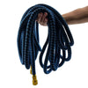 A hand is holding a coiled blue expandable high-pressure garden hose set with brass fittings.