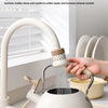 A person is using an extendable tap filter sprayer to purify water, with water flowing from the device into a sink.