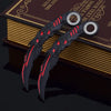 Ein Paar schwarze Drachenklaue-Modellmesser mit roten Akzenten, die auf einem dunkelbraunen, ledergebundenen Buch liegen.