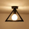 A black triangular chandelier lamp with an exposed light bulb hanging from a ceiling.