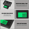 A black digital jewelry scale showing a large green LCD display and featuring a protective cover and tray.