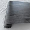 Roll of gray wood grain self-adhesive wall decals showing a textured, dark finish.