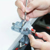 A hand is using a jeweler's saw to cut a piece of metal within an adjustable frame and vise setup.
