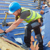 A construction worker wearing a blue hard hat and safety vest is working on a roof structure with wooden planks.