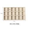 A rectangular beige jewelry storage tray with 18 compartments for plush velvet jewelry.