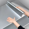 Une main applique un rouleau de vinyle d'aluminium sur une surface grise lisse.