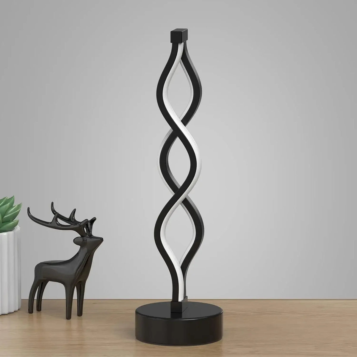A black and white spiral desk lamp with a deer silhouette base.