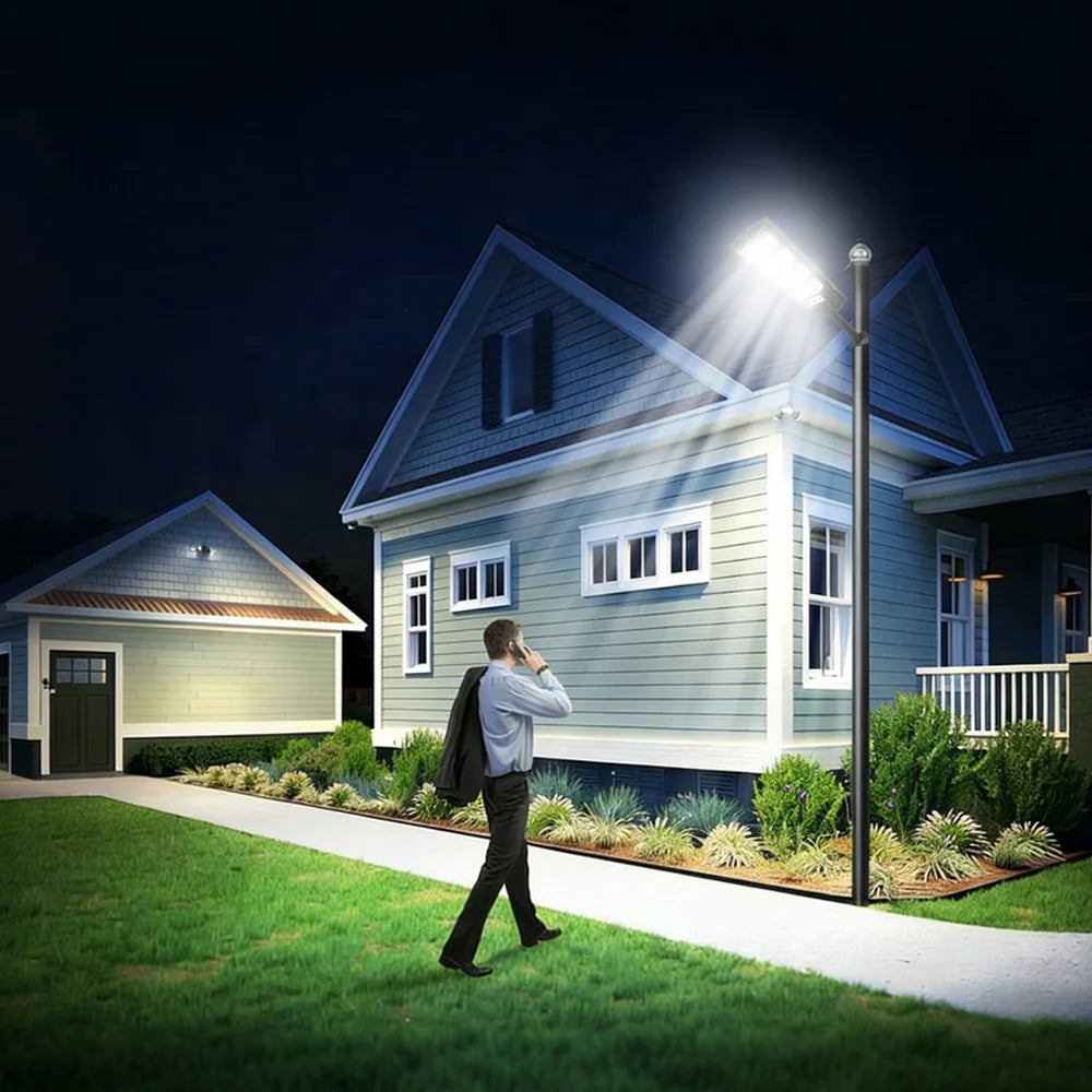 A person stands outside a house at night, adjusting an outdoor solar motion sensor LED light.