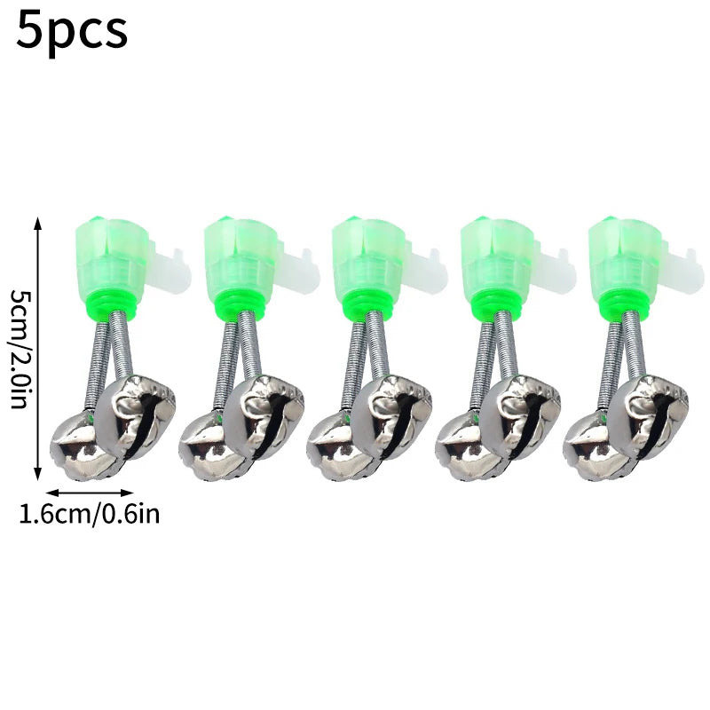 Cinco campanas de alarma para picadas de pesca plateadas con accesorios de plástico verde junto a una balanza.