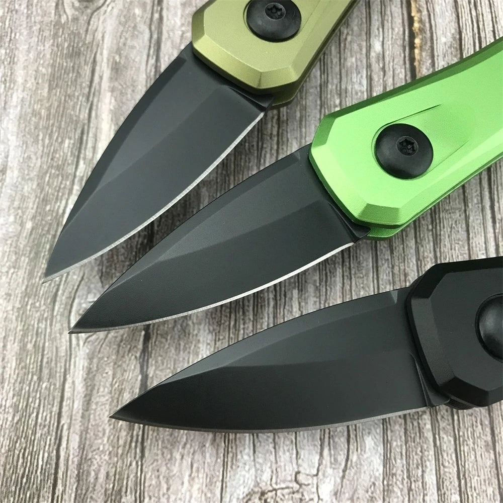 A close-up view of a compact folding pocket knife with a green and black blade and handle resting on a wooden surface.