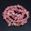 A collection of pink and clear rose quartz beads arranged in a circular pattern for jewelry making.