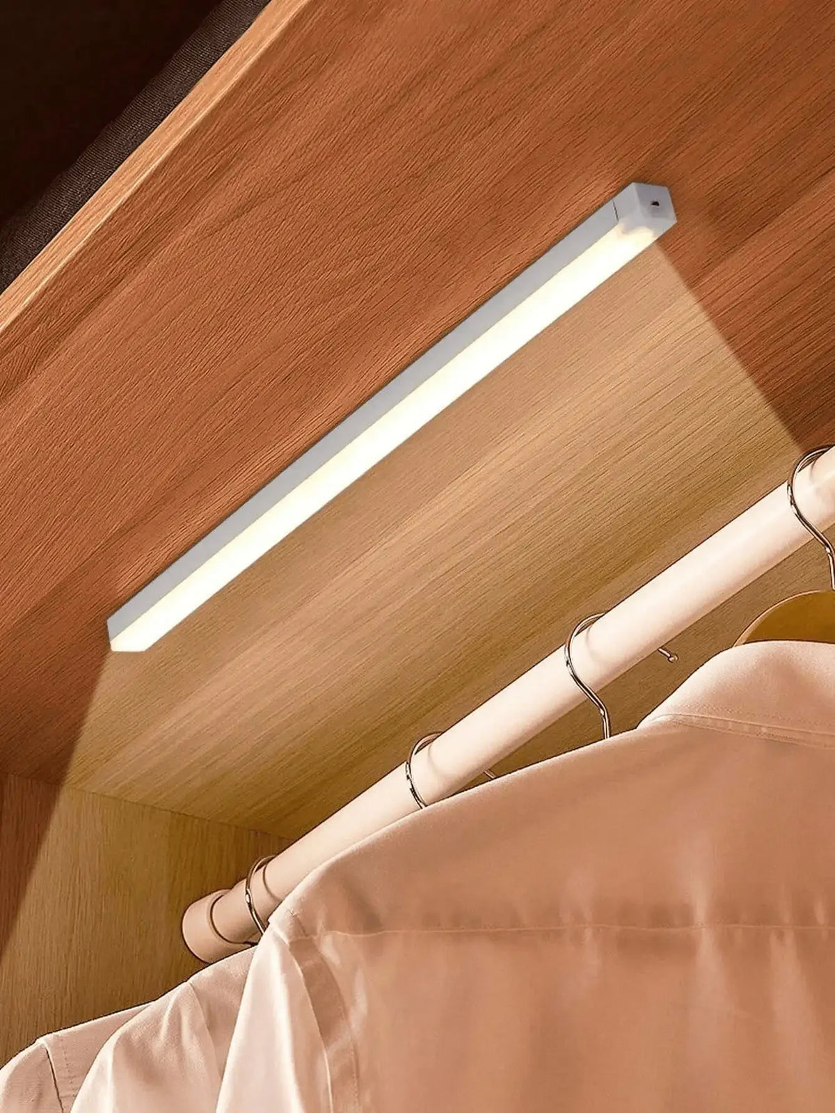 قضيب إضاءة LED أبيض طويل مثبت تحت خزانة خشبية، يضيء الداخل.