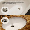 Close-up view of a white bathtub drain with a stainless steel hair catcher and a decorative metal drain plug.