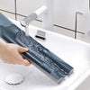 A hand is applying a dark blue windproof door draft excluder seal strip to a white sink.