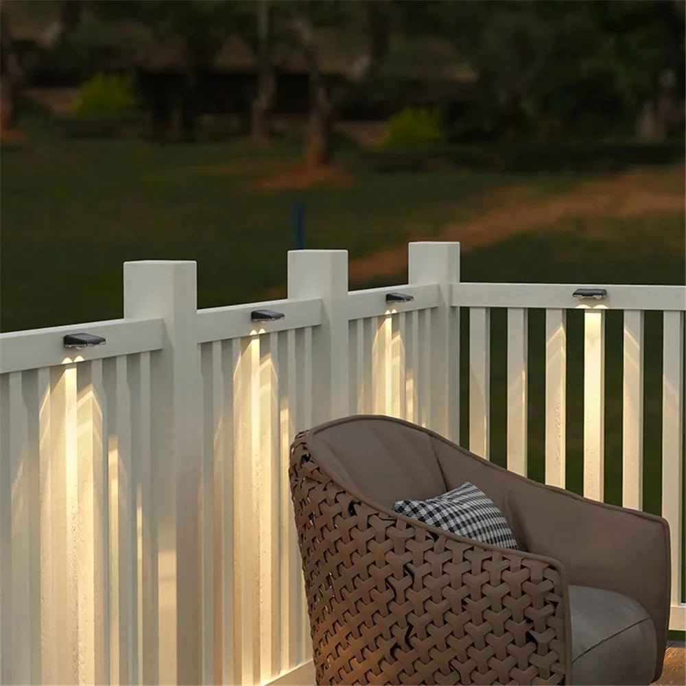 Weiße vertikale Lamellen-Solar-LED-Wandleuchte, die einen Garten oder Außenbereich beleuchtet.