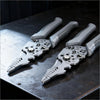 A pair of heavy duty stainless steel wire stripper pliers resting on a dark surface.