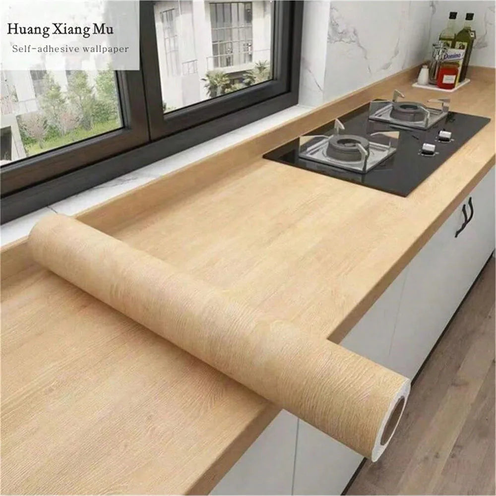 Roll of wood grain vinyl wall contact paper next to a window with a black stovetop counter.