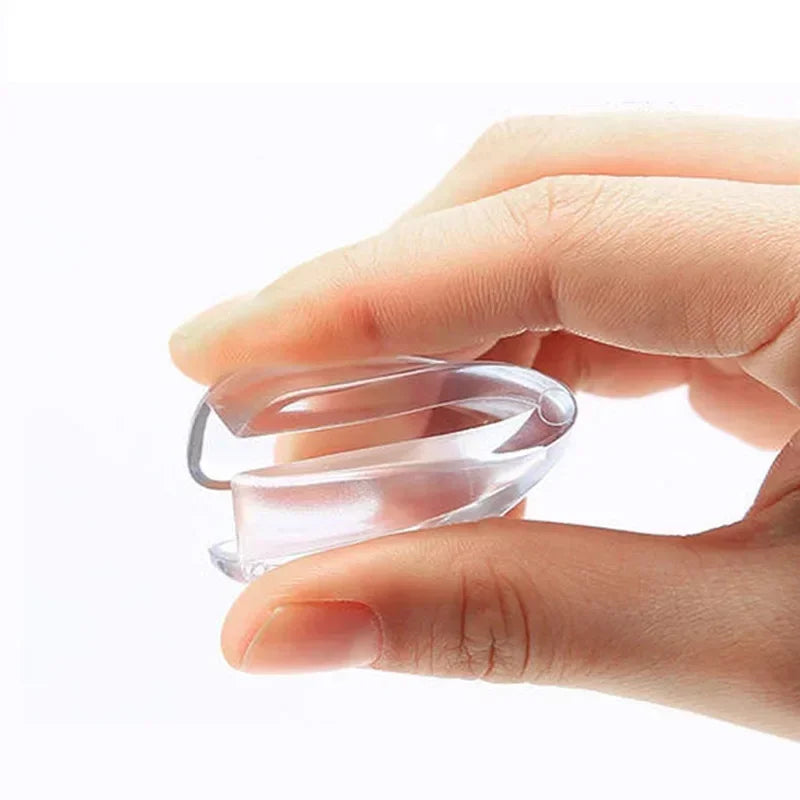 A hand holds a clear silicone corner edge protector for baby safety