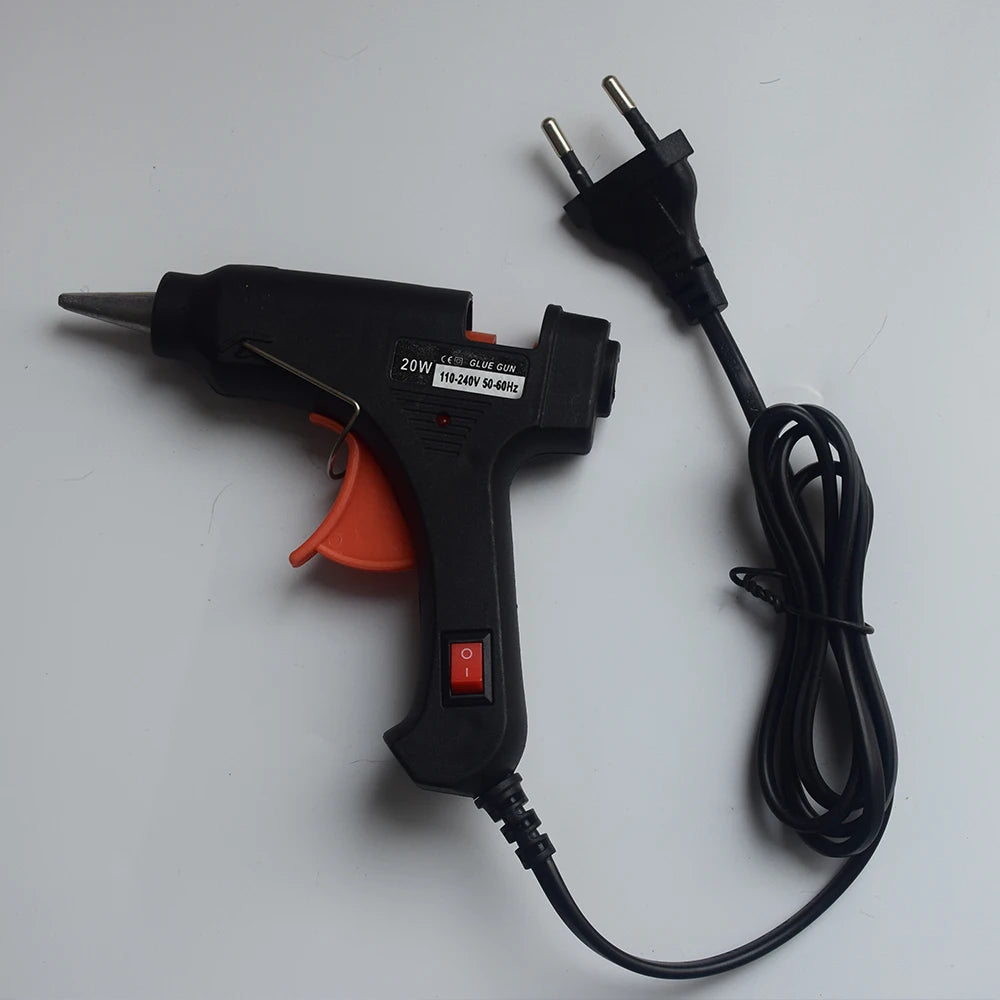 A black hot melt glue gun with an attached power cord and nozzle is shown on a white surface.