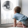 A baby is looking at an adjustable aluminum window lock stopper mounted on a white window frame.