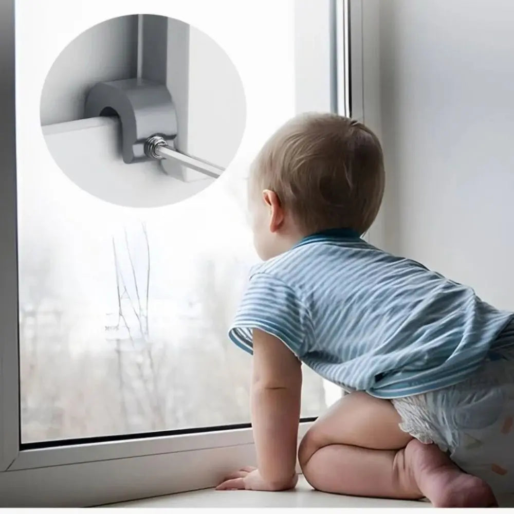 A baby is looking at an adjustable aluminum window lock stopper mounted on a white window frame.
