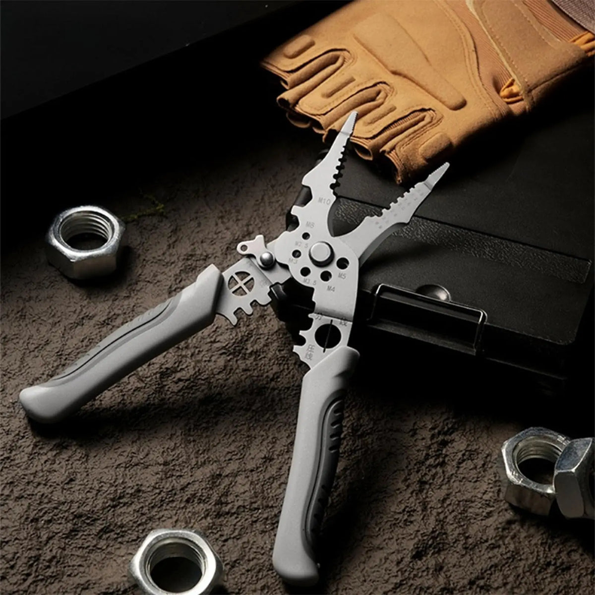 A heavy duty stainless steel wire stripper pliers with a silver handle and teeth, resting on a dark surface next to a tan glo
