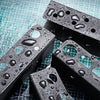 A black heavy duty wall mounted tool storage rack with holes, covered in water droplets, resting on a blue grid surface.