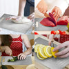 Manos preparan diferentes alimentos como carne, verduras y cítricos en una tabla de cortar de acero inoxidable.