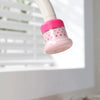 A pink and white extendable tap filter sprayer is shown hanging from a white pipe, designed for water saving.