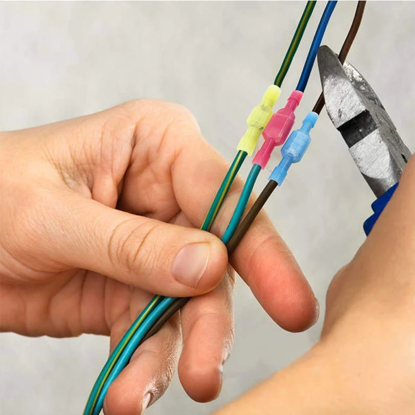 A hand is holding and manipulating several insulated crimp terminals with various colored connectors.