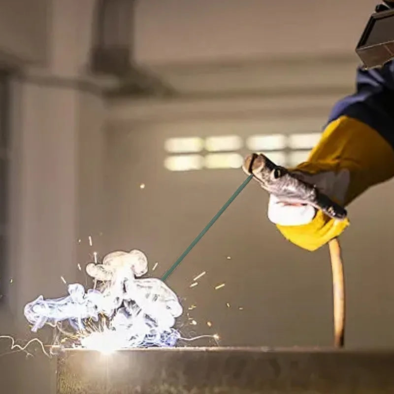 A person is using a green welding rod to create sparks on a metal surface.