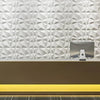 A modern reception desk with a backlit yellow surface in front of a textured white geometric wall panel.