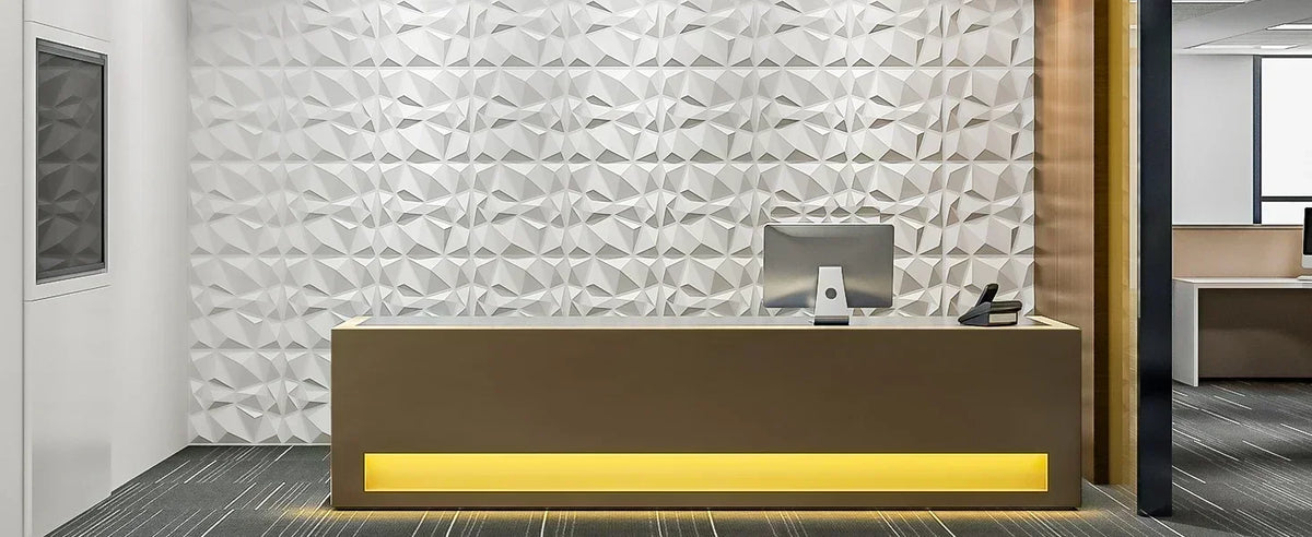 A modern reception desk with a backlit yellow surface in front of a textured white geometric wall panel.