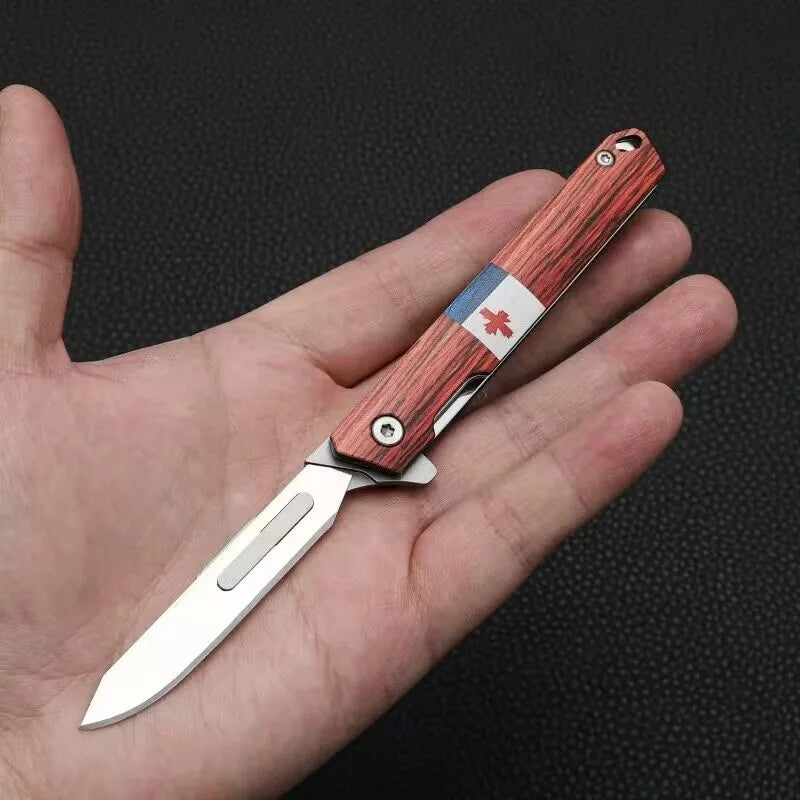 A hand holds a portable utility folding knife with a wooden handle and a blue and white marking.