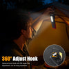A hand is hanging a 360 degree adjust hook light onto a tent fabric in the dark.