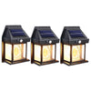 A set of three black solar motion sensor outdoor wall lights with glass bulbs and solar panels.