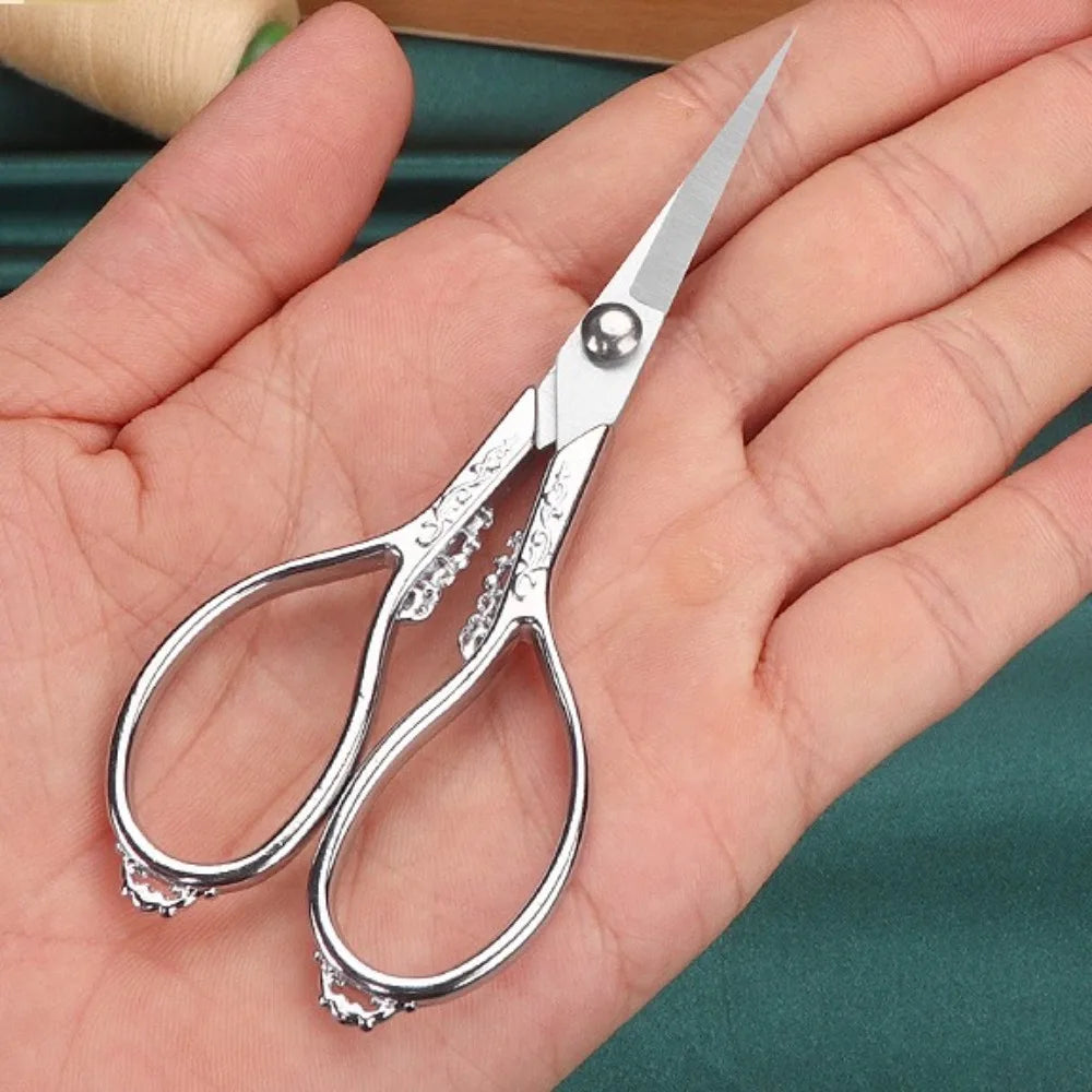Un par de tijeras de detalle profesionales de acero inoxidable sujetadas en la mano de una persona.