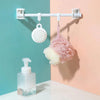 A white curtain rod with hanging brackets holds a pink and white fluffy fabric item against a light peach wall.