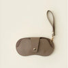 A brown PU leather eyeglasses case with a lychee pattern and a thin strap.