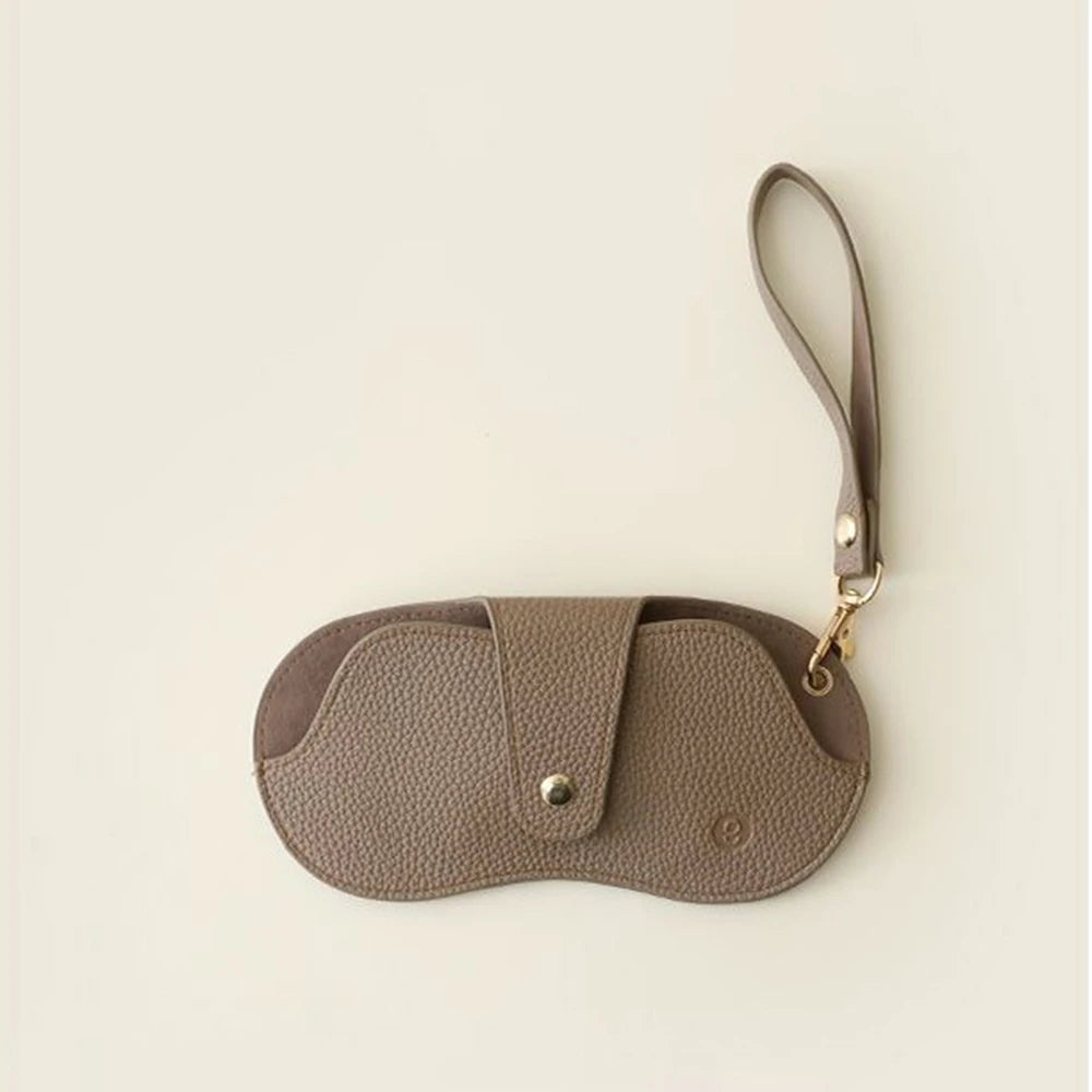 A brown PU leather eyeglasses case with a lychee pattern and a thin strap.