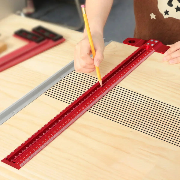 A hand is using a yellow pencil to mark a precision red T-square on a wooden surface for woodworking.