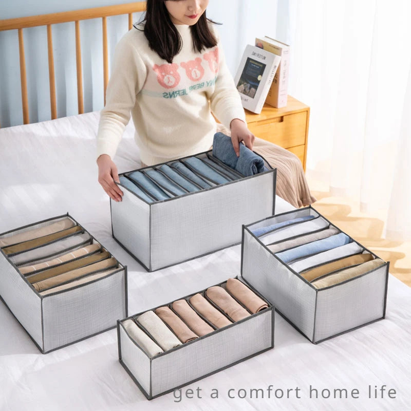 A person is organizing fabric into various storage boxes on a bed, demonstrating the versatile fabric storage organizer box.