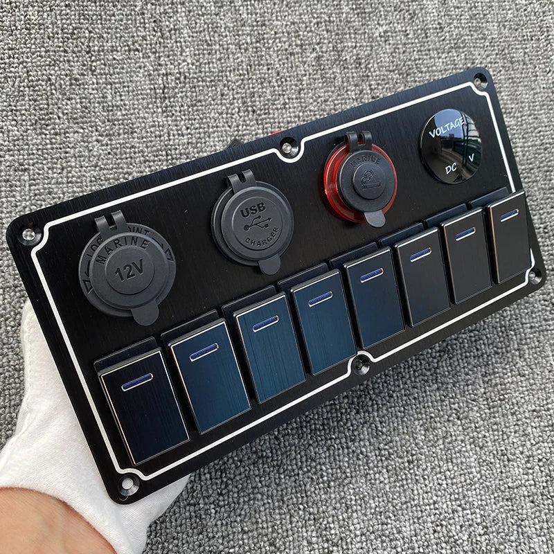 Un panneau de commutateur noir avec divers ports DC et USB repose sur une surface en tissu gris.