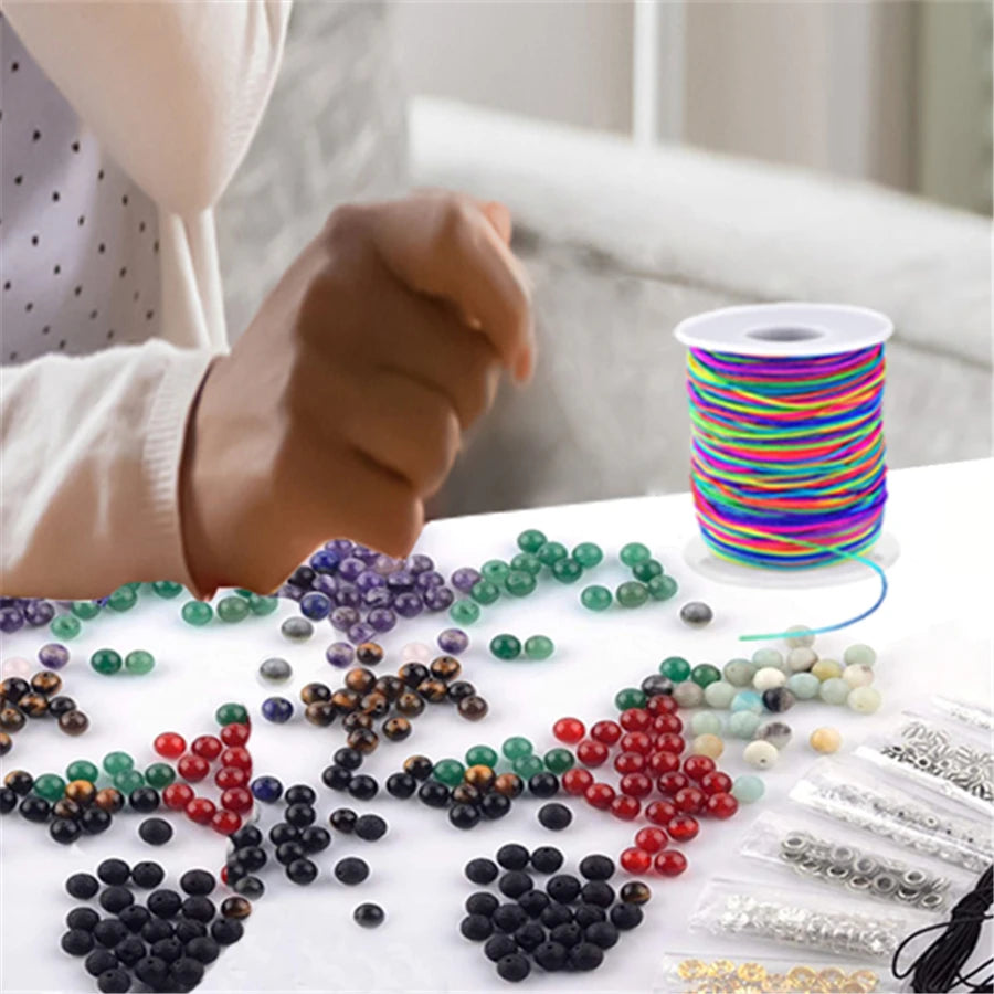 A collection of colorful, multi-colored elastic cords and beads for jewelry making displayed on a white surface.